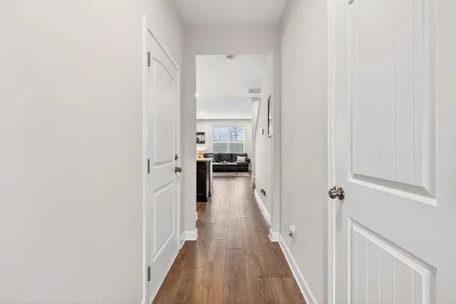 a view of a hallway with a white walls and wooden floor