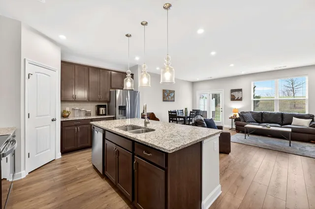 a kitchen with a stove a refrigerator a sink dishwasher with a dining table and chairs with wooden floor