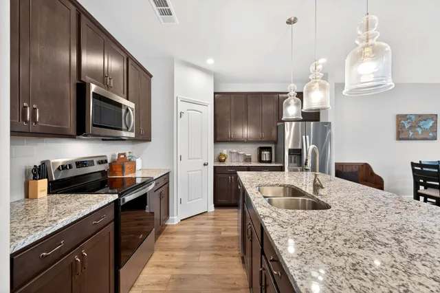a kitchen with stainless steel appliances granite countertop a sink stove and refrigerator