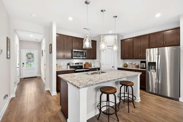a kitchen with granite countertop a center island stainless steel appliances and wooden cabinets