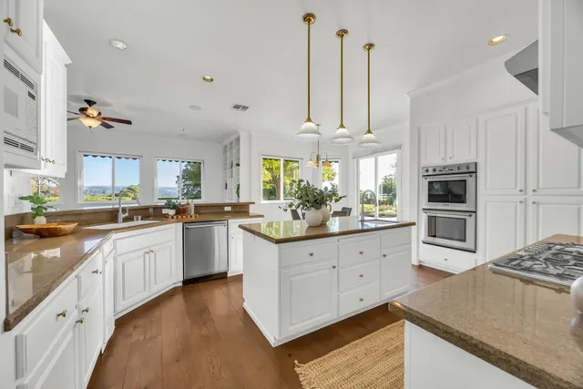 a kitchen with stainless steel appliances granite countertop a stove and white cabinets