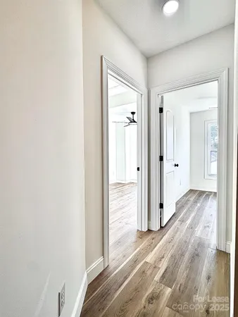 a view of empty room with wooden floor and fan
