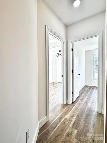 a view of empty room with wooden floor and fan