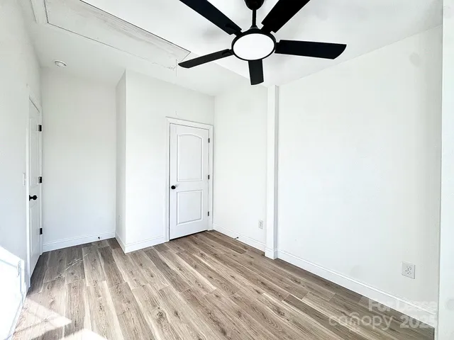a view of empty room with wooden floor and window
