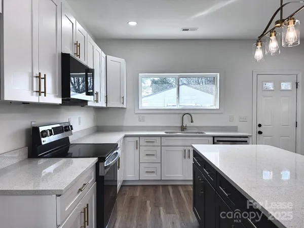 a kitchen with stainless steel appliances granite countertop a stove a microwave and a window