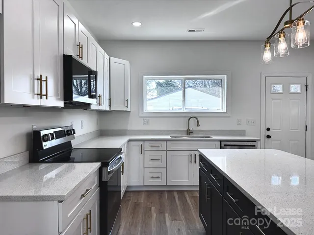 a kitchen with stainless steel appliances granite countertop a stove a microwave and a window