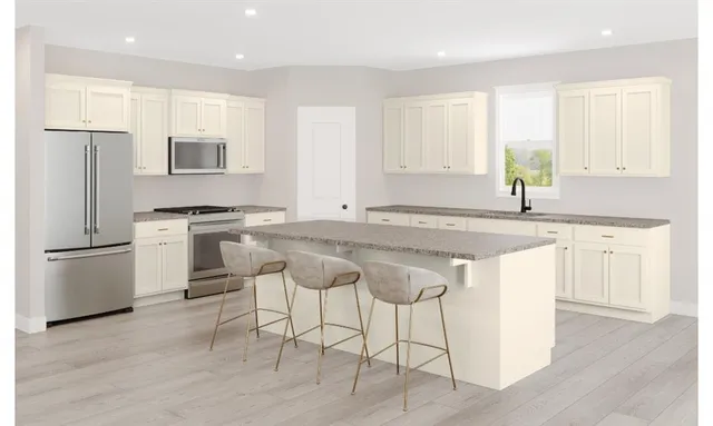 a kitchen with stainless steel appliances granite countertop a stove a sink a refrigerator and white cabinets with wooden floor