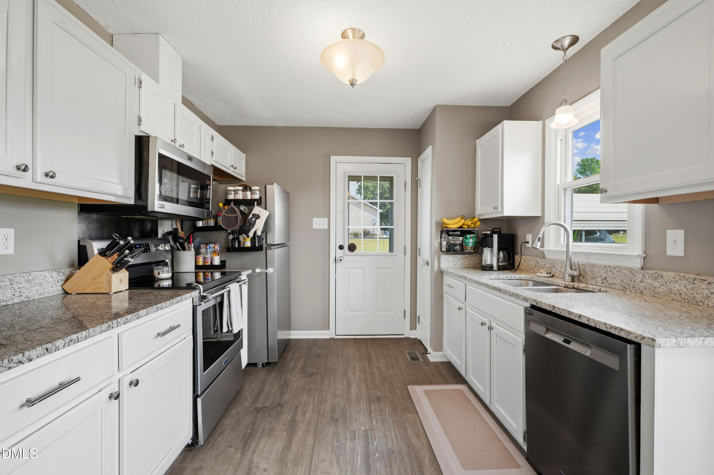 101 Stephenson Road Benson, NC 27504 - Photo 9 of 29 a kitchen with stainless steel appliances granite countertop a refrigerator a sink dishwasher a stove and white countertops with wooden floor