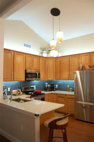a kitchen with stainless steel appliances a refrigerator a sink a stove a microwave a dining table and chairs