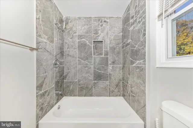a bath tub sitting next to a white toilet and a shower curtain