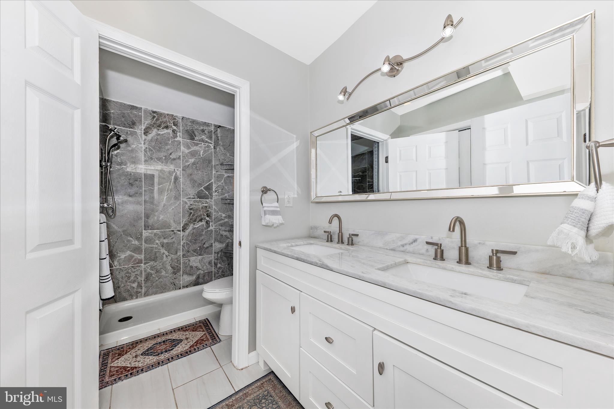 6216 Manor Woods Road Frederick, MD 21703 - Photo 30 of 45 a bathroom with a granite countertop sink a mirror a vanity and shower