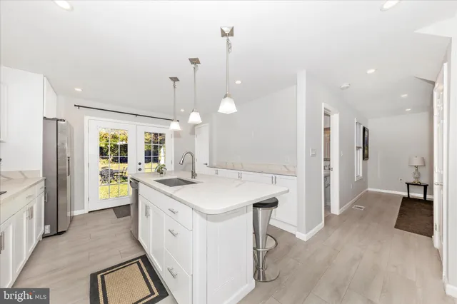 a kitchen with a sink a counter top space stainless steel appliances and a chandelier