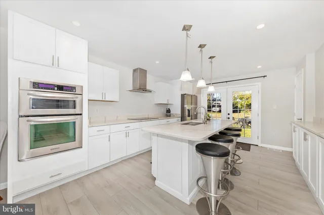 a kitchen with stainless steel appliances a stove a sink cabinets and a wooden floor