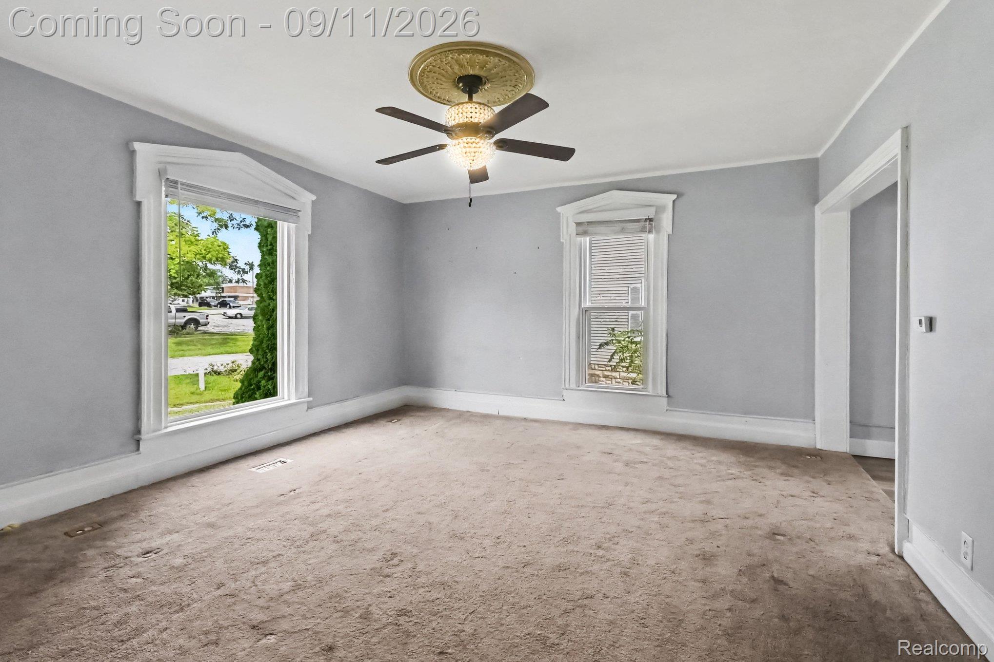 409 Fleming Street Howell, MI 48843 - Photo 14 of 25 Ceiling fan with chandelier lighting, decorative ceiling medallion, ornate window trim, a second window, and a wide doorway