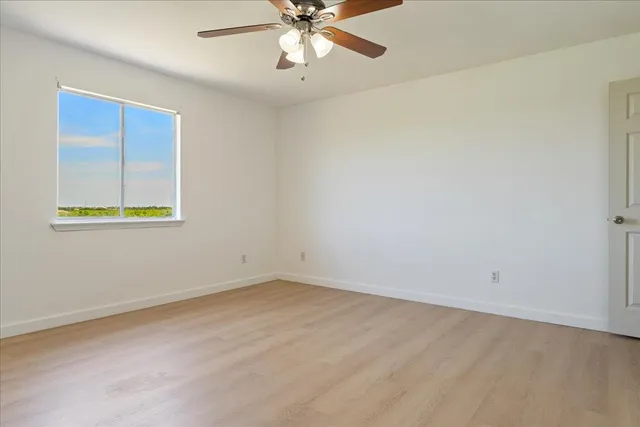 an empty room with a window and a fan