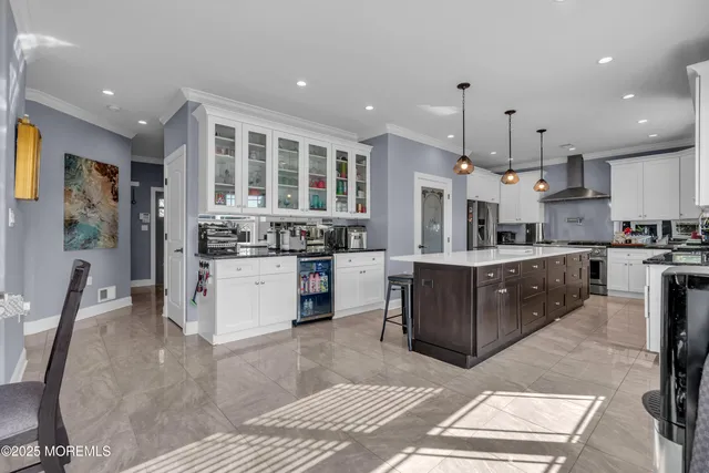 a kitchen with stainless steel appliances kitchen island granite countertop a stove a sink a refrigerator and a dining table with wooden floor