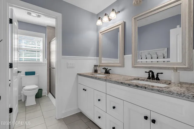 a bathroom with a granite countertop sink mirror and toilet
