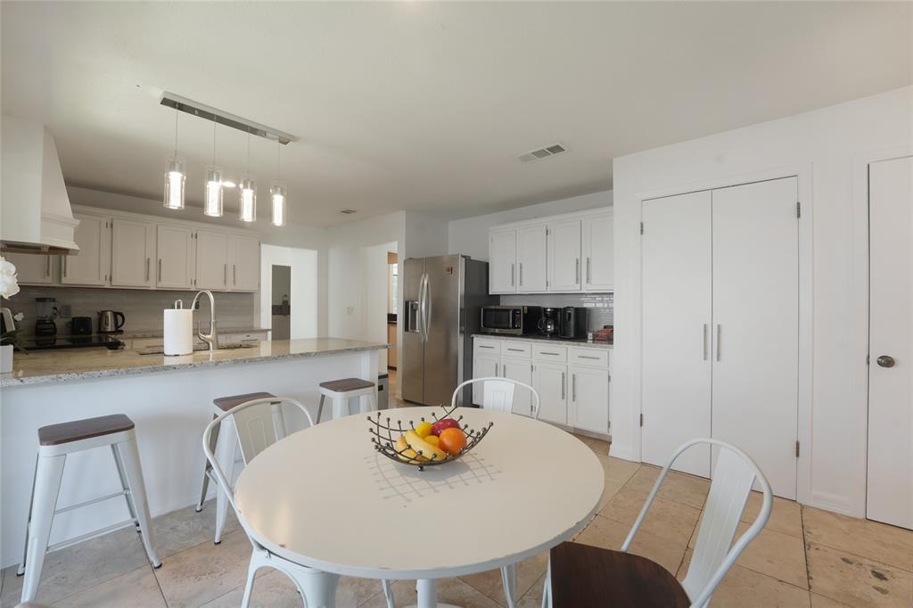 9677 Fallbrook Drive Dallas, TX 75243 - Photo 34 of 40 a kitchen with stainless steel appliances wooden floor dining table and chairs