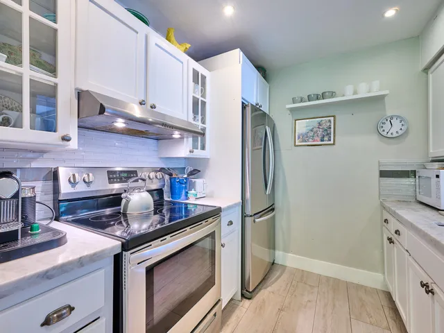 a kitchen with stainless steel appliances granite countertop a refrigerator and a stove top oven