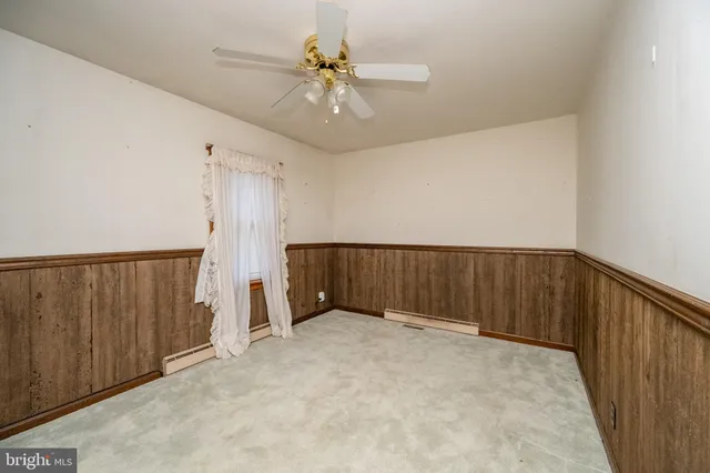 an empty room with a ceiling fan and carpet