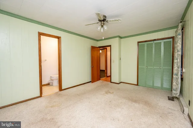 an empty room with closet and a chandelier fan