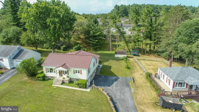 an aerial view of a house with swimming pool and large trees