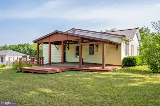 a backyard of a house with table and chairs under an umbrella