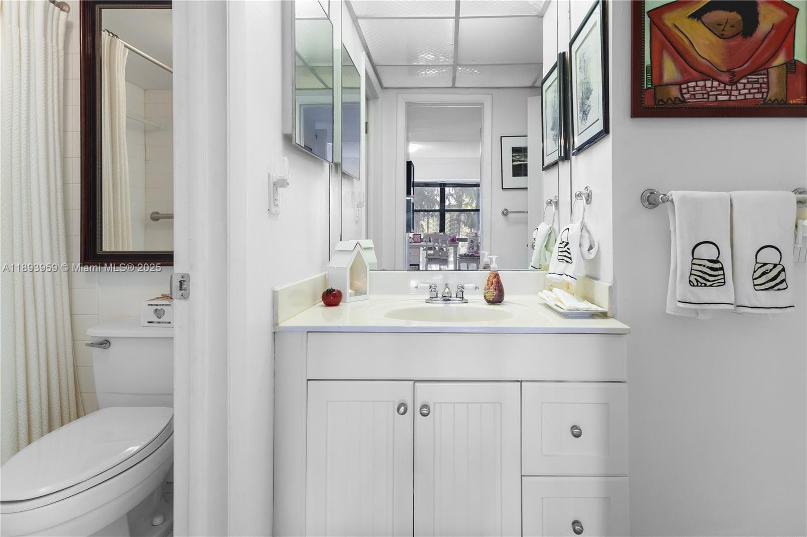 77 Crandon Boulevard, Unit 3C Key Biscayne, FL 33149 - Photo 23 of 34 a bathroom with a sink a toilet and a mirror