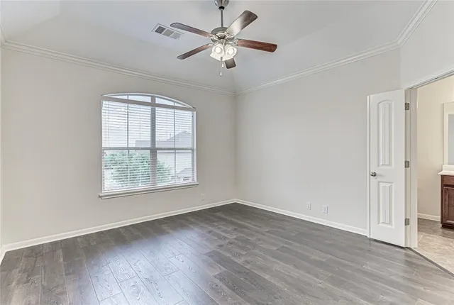 an empty room with wooden floor ceiling fan and windows