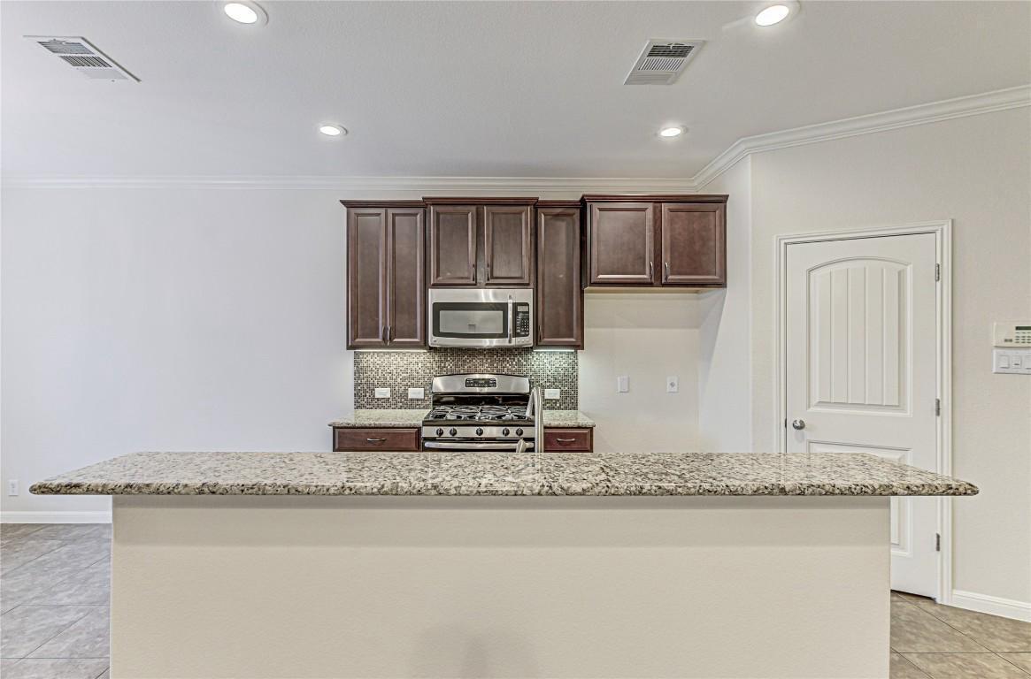 14001 Avery Ranch Boulevard, Unit 103 Austin, TX 78717 - Photo 8 of 29 a kitchen with stainless steel appliances granite countertop a stove a sink and a microwave