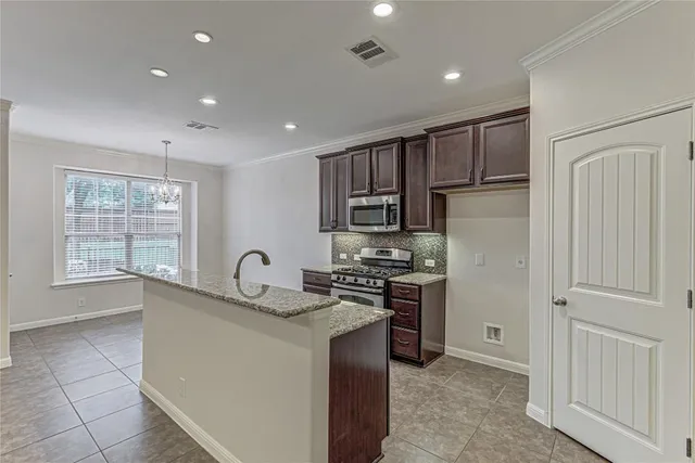 a kitchen with stainless steel appliances granite countertop a stove a sink and a refrigerator