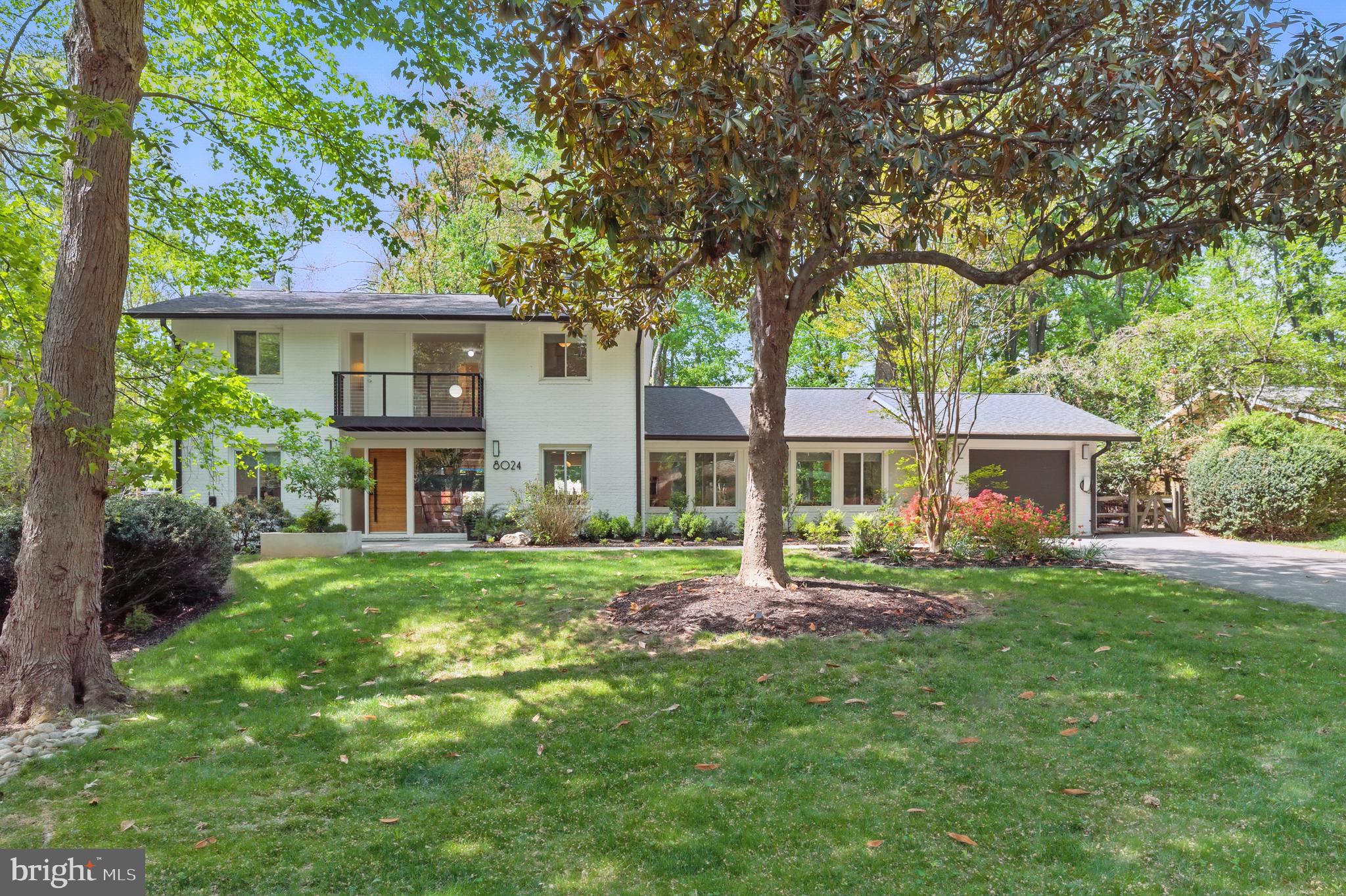 a view of a house with a yard deck and a large tree
