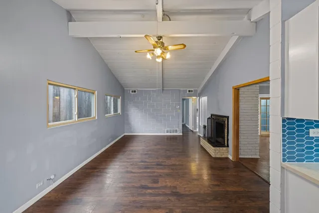 a view of a livingroom with a chandelier fan kitchen view and a refrigerator