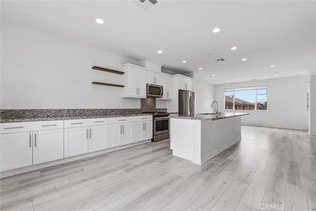a view of an empty room with wooden floor and a bathroom