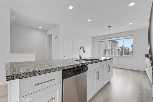 a large kitchen with stainless steel appliances granite countertop a large counter top and a stove with wooden floor