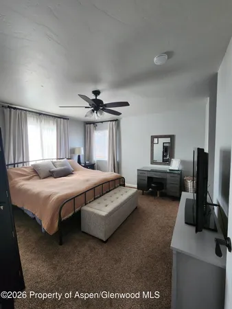 a spacious bedroom with a bed a computer on the desk and a couch