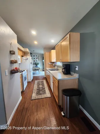 a large white kitchen with stainless steel appliances granite countertop a stove a sink and a refrigerator