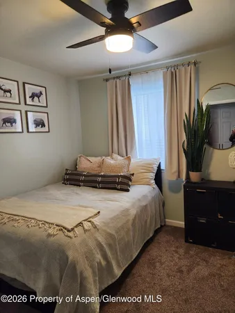 a bedroom with a bed and a flat tv screen on dresser