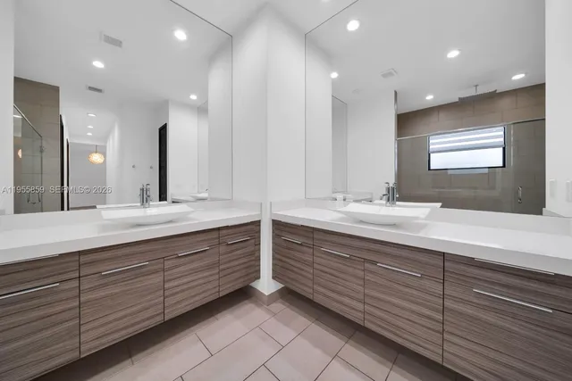 a bathroom with double vanity and a large mirror