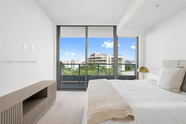 a large white bed in a bedroom next to a window