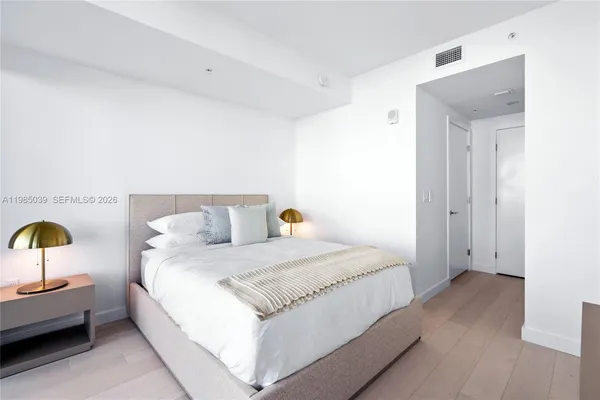 a bedroom with a bed and a lamp next to a window