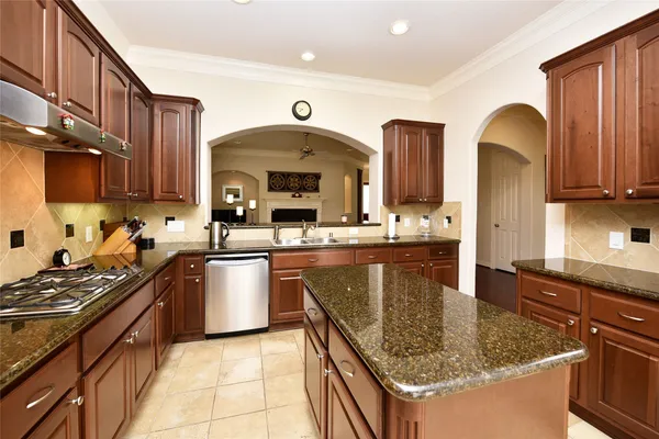 a kitchen with stainless steel appliances granite countertop a sink dishwasher stove and refrigerator with wooden cabinets