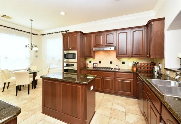 a kitchen with kitchen island granite countertop a sink counter top space appliances and cabinets