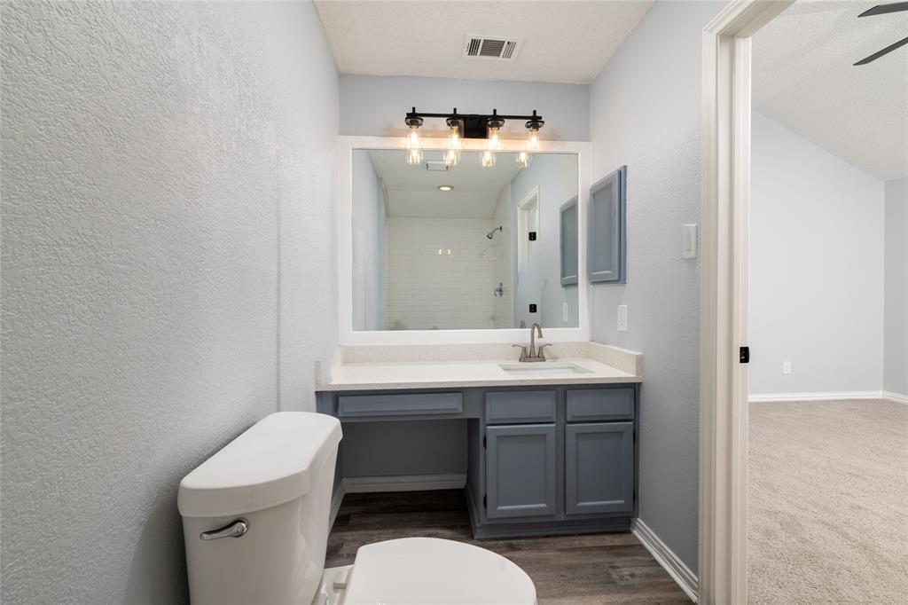 2513 Poplar Spring Road Fort Worth, TX 76123 - Photo 29 of 40 Vanity with integrated sink, wood-like LVP flooring, built-in cabinetry, and a framed mirror