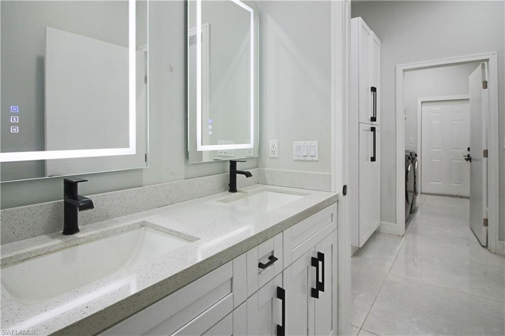 3902 4th Street Southwest Lehigh Acres, FL 33976 - Photo 23 of 34 Dual vanity with integrated sinks, light-colored countertop, and matte black waterfall faucets