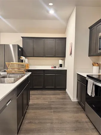 a kitchen with stainless steel appliances granite countertop a sink counter space cabinets and wooden floor