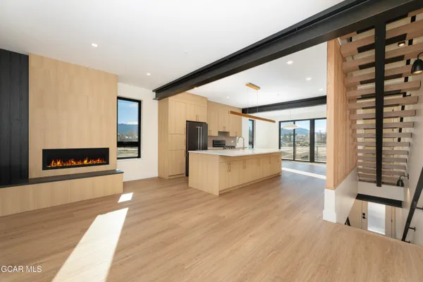 a living room with stainless steel appliances kitchen island granite countertop a refrigerator a sink and a large window