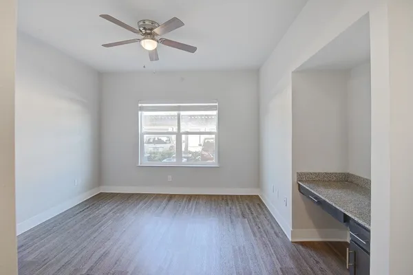 an empty room with wooden floor chandelier fan and windows