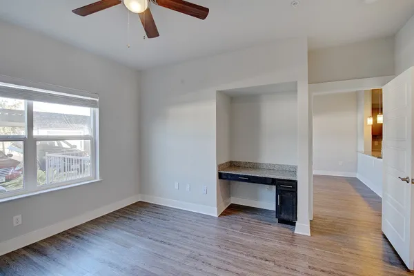 an empty room with wooden floor fan and windows