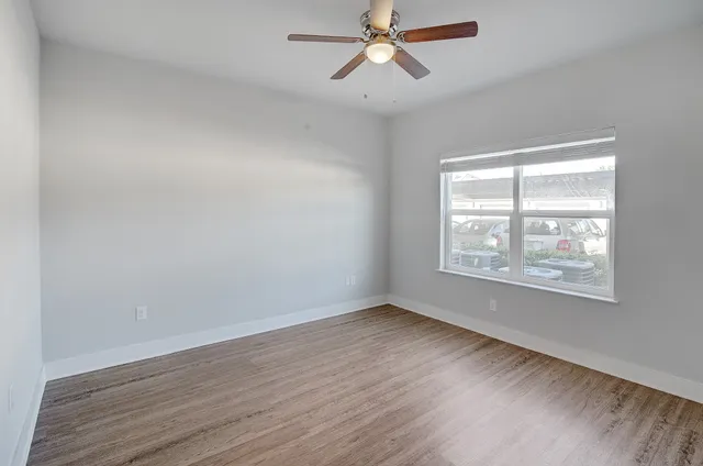 a view of an empty room with wooden floor and a window